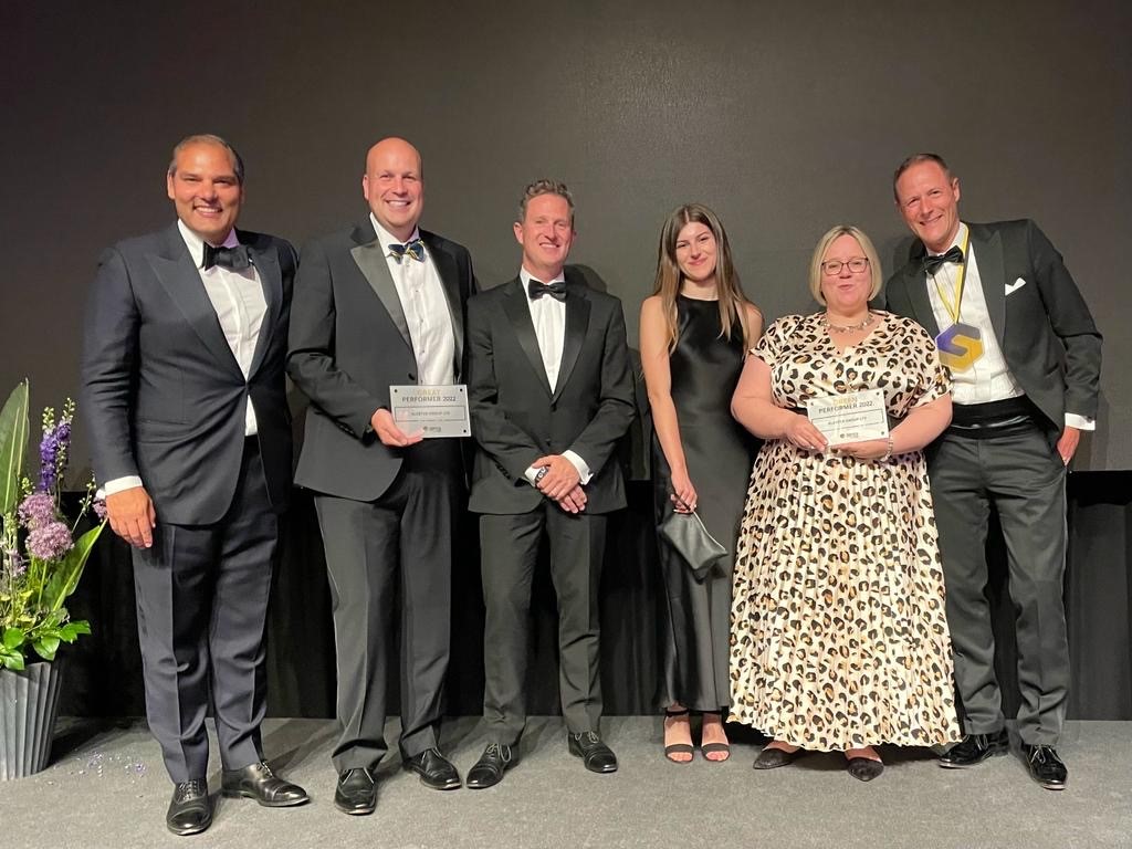 A photo of some members of the Alerter Group and Sdiptech team. They are standing at an awards show and are dressed formally. Two team members are holding awards.
