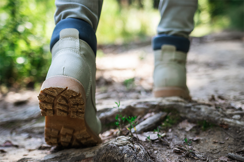 A person walks along a muddy path in hiking boots.